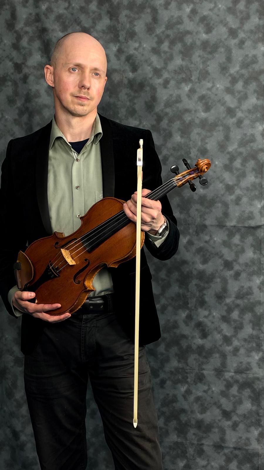 Benjamin Errington standing with his viola and bow